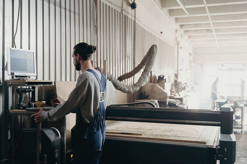 Opérateur pilotant une table de découpe numérique dans un atelier