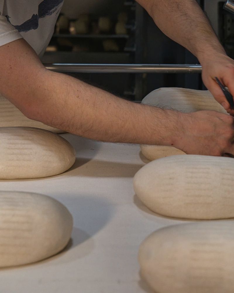 Mains d’un boulanger façonnant des pâtons dans une boulangerie artisanale