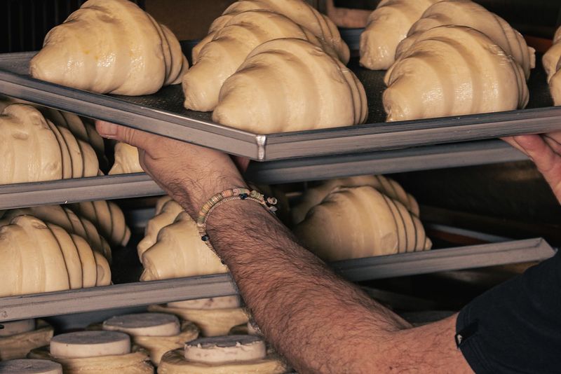 Boulanger enfournant des plaques de croissants dans un four professionnel
