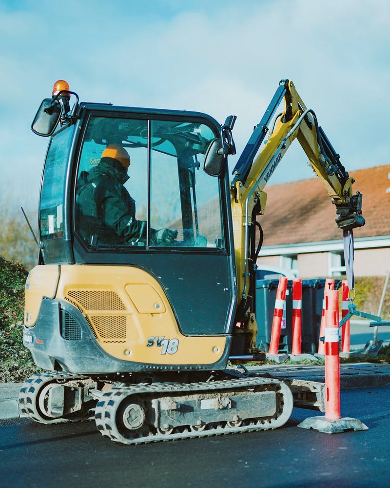 Opérateur casqué aux commandes d’une mini-pelle sur un chantier de voirie